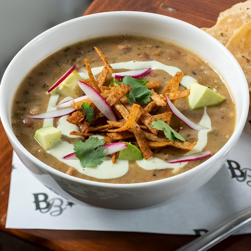 A bowl of Bar Bacoa's tortilla soup with avocado, radishes, cilantro, and tortilla strips.