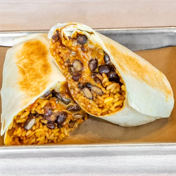 Two halves of a Bar Bacoa burrito, filled with rice, black beans, and melted cheese.