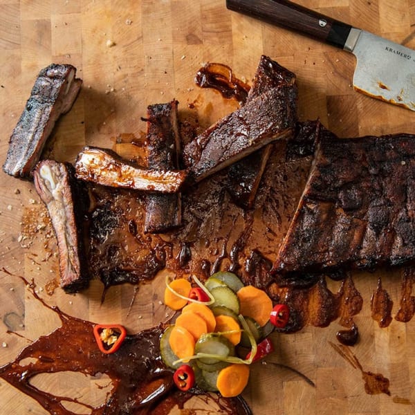 Bar Bacoa's glazed ribs with pickled vegetables and a knife on a wooden cutting board.